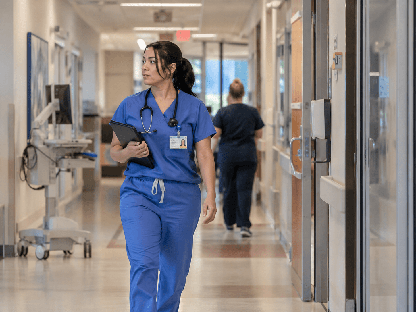 A credentialed clinician moving through a hospital corridor, the end result of a credentialing file that cleared committee on time.